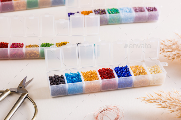 Containers with colored beads, wire and scissors for beading. Needlework and handmade