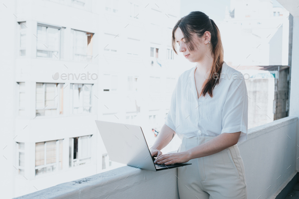 Young woman businesswoman freelancer using laptop for work outdoors on a balcony. Freelance work