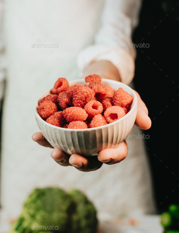 Close up image of an old woman cooking chef grabbing raspberry offering ...