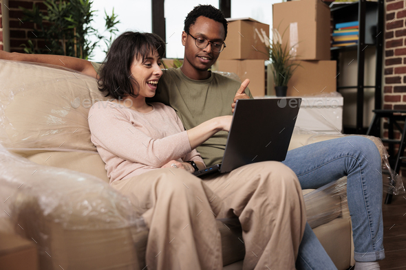 Diverse couple doing online shopping on laptop to buy furniture