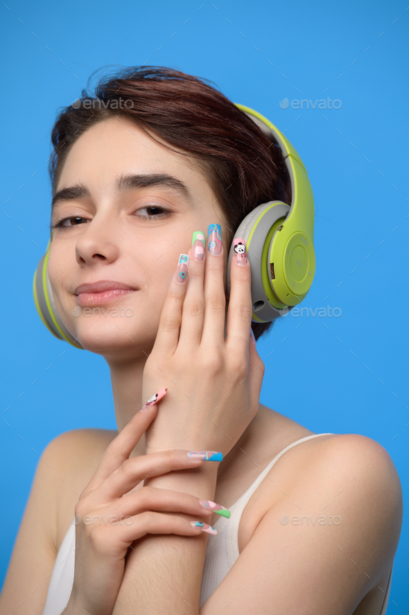 Cute young brunette listening to music using bluetooth wireless headphones