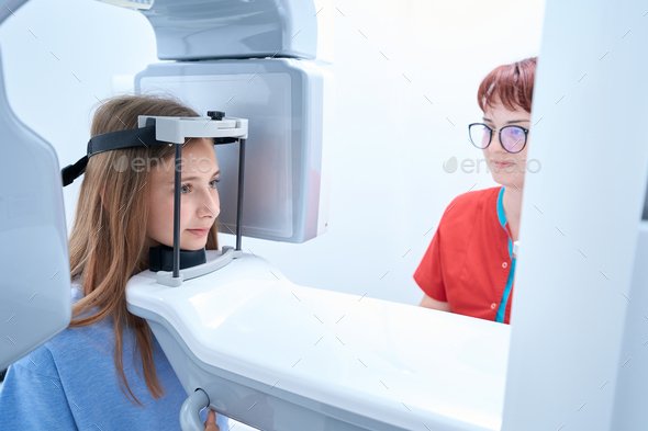 Young lady getting digital panoramic x-ray in presence of doctor