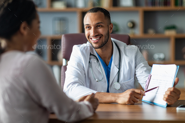 Cheerful doctor showing black lady patient treatment plan