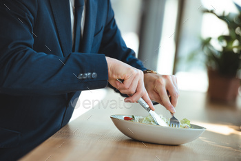 partial view of businessman at table with served lunch in restaurant