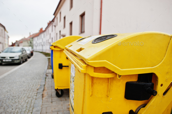 Yellow trash cans for plastic in street.