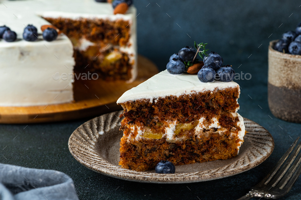 piece of carrot cake with walnuts and blueberry on dark wood background. Local food.