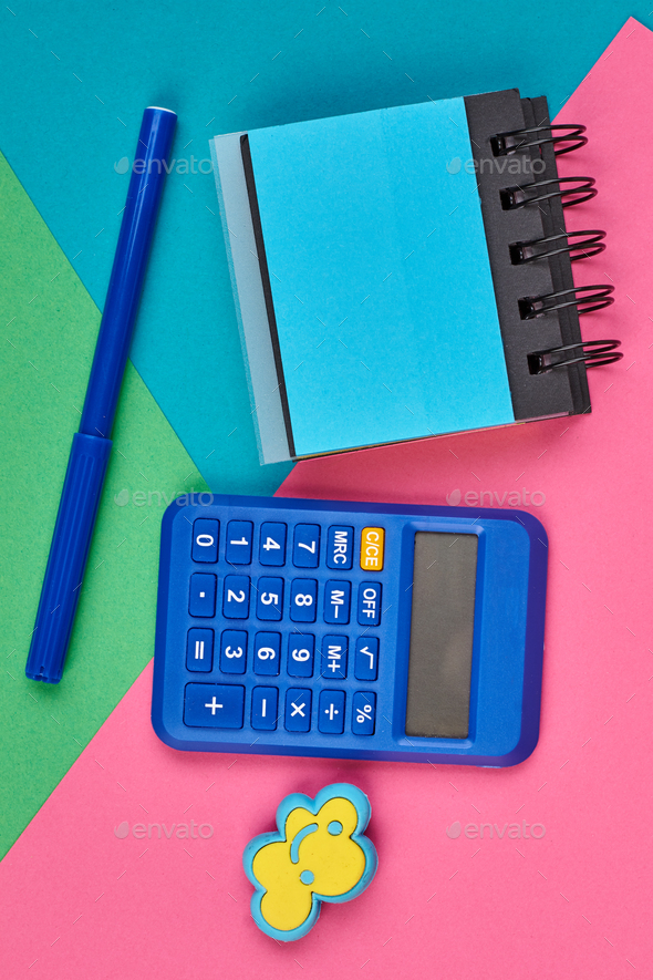 Calculator, notepad and marker on color background.