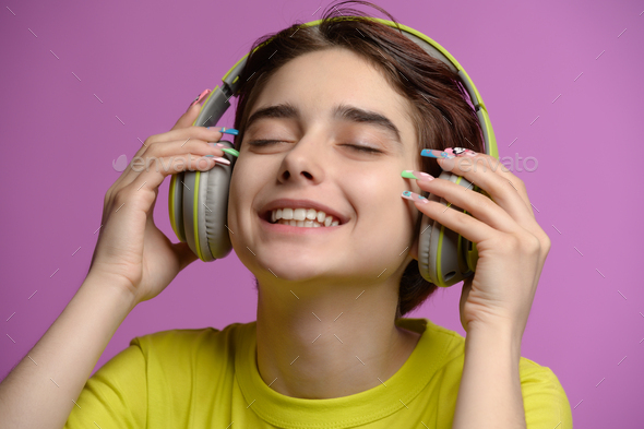 Cute young brunette having fun listening music using wireless headphones