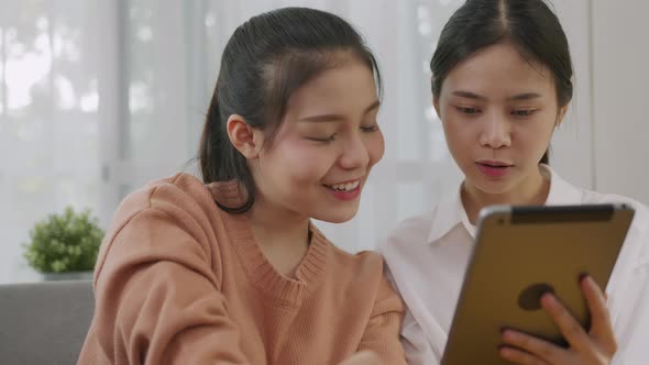 Cheerful beautiful Asian with friends using smartphone and tablet on social media. alt