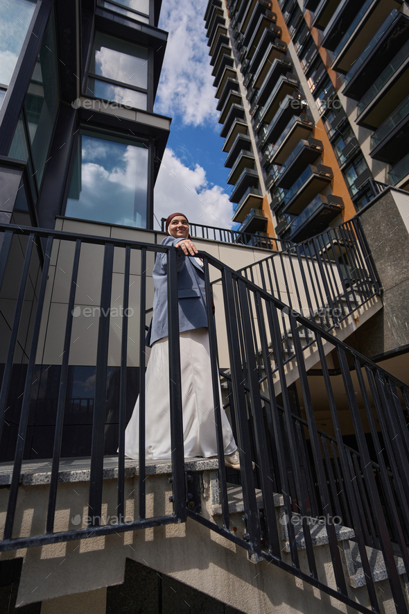 Muslim woman descends the stairs against the backdrop of high-rise buildings