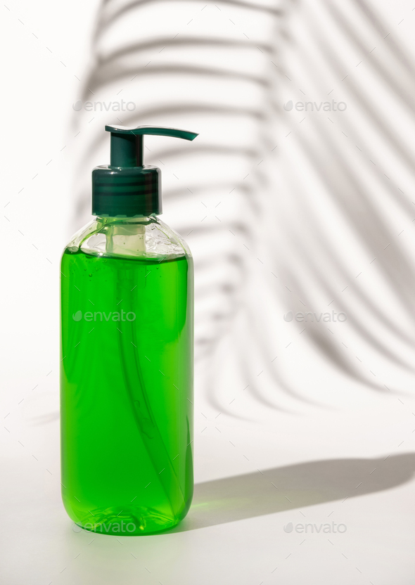 Cosmetic pump dispenser bottle filled with green liquid on white, Palm leaf hard shadows