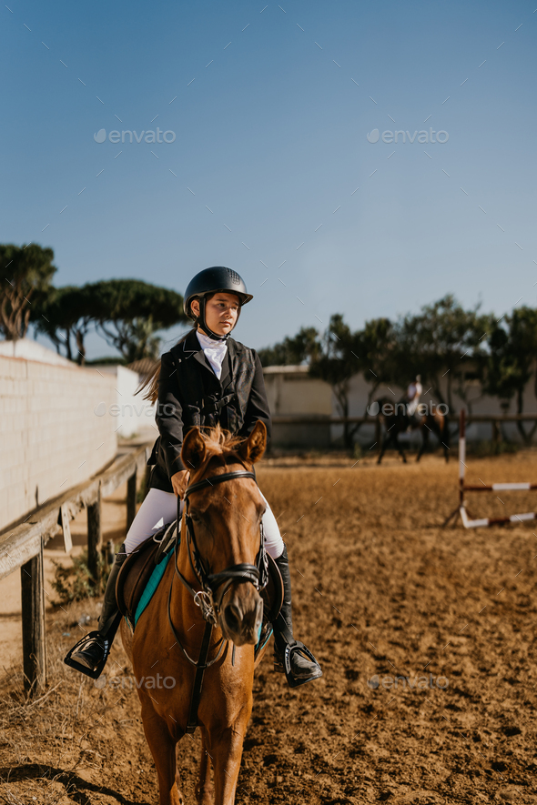 15-year-old warming up a brown horse in the equestrian arena