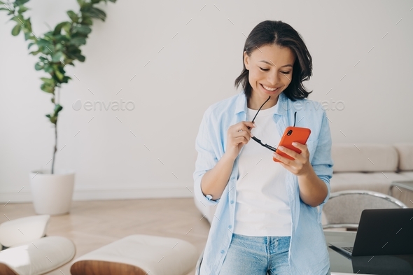 Businesswoman has online discussion in chat, texting on phone and smiling at home office.