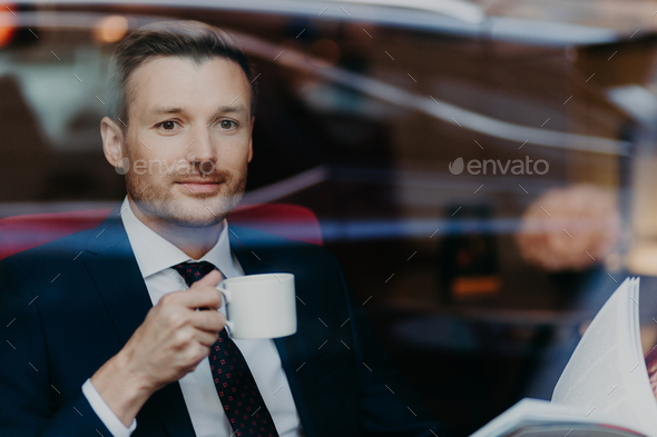 businessman in formal suit, drinks coffee during dinner break, sits in luxury cafe