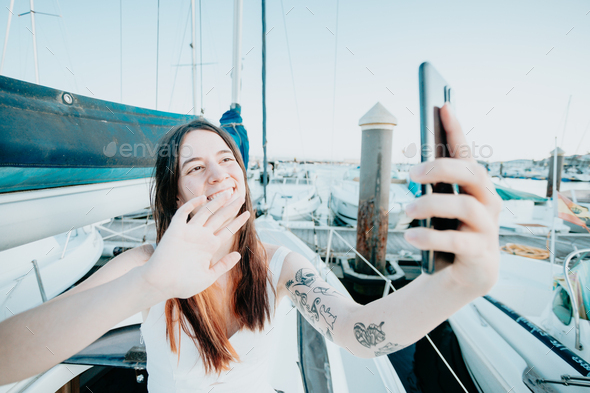 A young cheerful woman taking selfie on a yacht share on social media showing off after sailing
