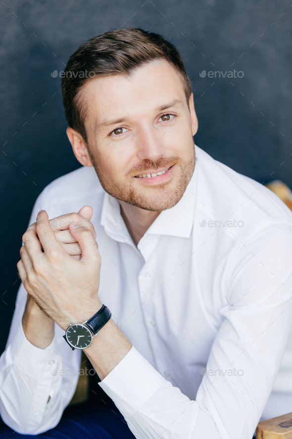 Elegant cheerful male office worker, keeps hands together, dressed in ...