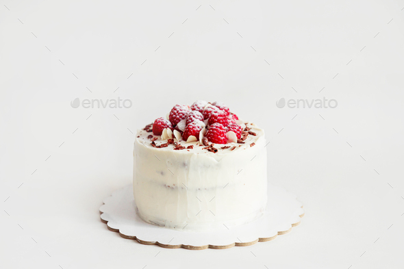Raspberry white mastic cake decorated fresh berries on cake stand, white table