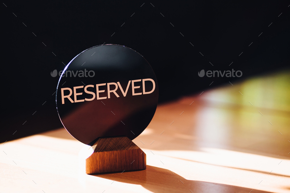 restaurant table reseved by client. Reservation sign on table against blurred background