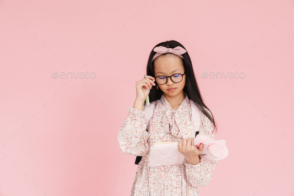Asian girl wearing eyeglasses writing down notes in exercise book - Stock Photo - Images