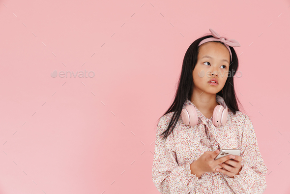 Asian puzzled girl with headphones using mobile phone - Stock Photo - Images