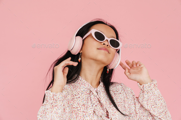 Asian girl dancing while listening music with headphones - Stock Photo - Images