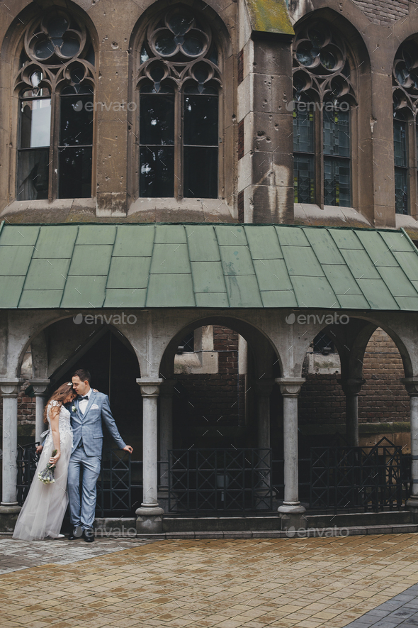 Stylish bride and groom embracing on background of old church. Romantic moment. Provence wedding