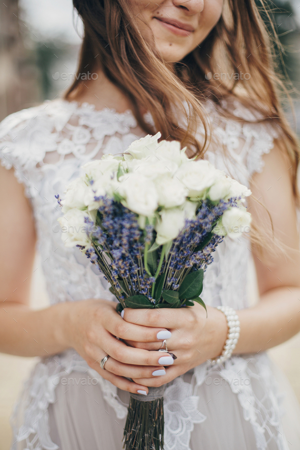 Portrait of bride with wedding bouquet of roses and lavender in stylish gown. Provence wedding