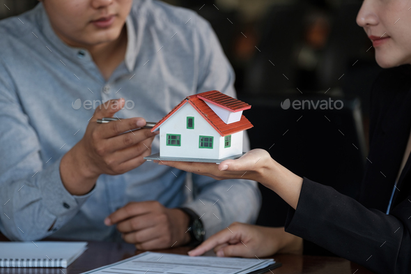 Real estate agent sales manager holding house model to customer after signing rental lease contract