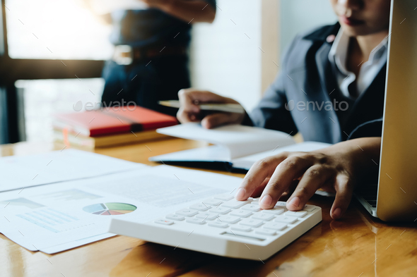 Business woman using calculator for do math finance on wooden desk in office - Stock Photo - Images