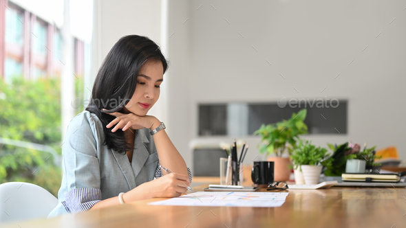 Concentrated female employee checking financial report, reports statistics financial.