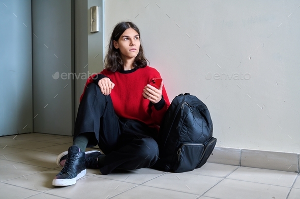Sad teenage guy sitting on floor near elevator inside building