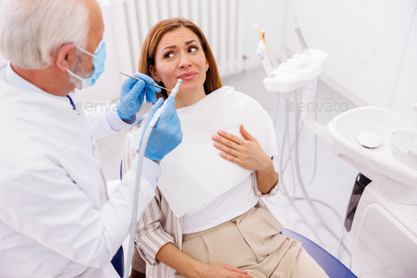 Woman scared while doctor is fixing her tooth at dentist office