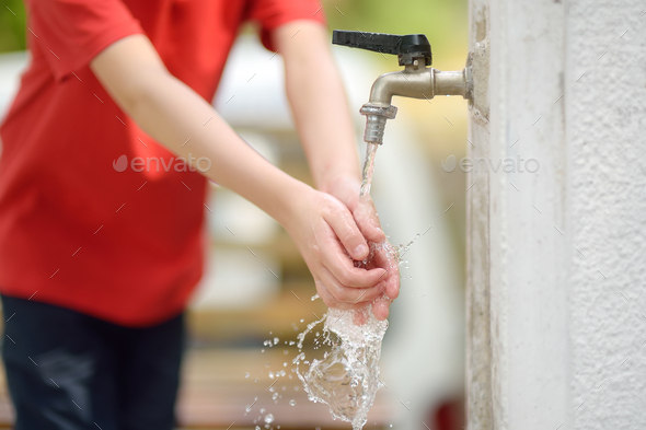 Closeup photo of child washing hands in a city fountain Stock Photo by ...