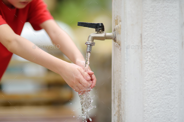 Closeup photo of child washing hands in a city fountain Stock Photo by ...