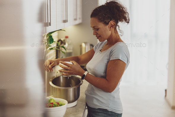 A woman prepares dough in the kitchen with a dough mixer