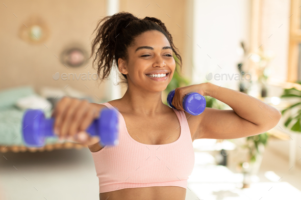 Training with weights. Happy african american woman doing exercises with  dumbbells, strengthening Stock Photo by Prostock-studio