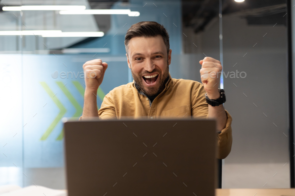 Emotional Business Man Shouting Shaking Fists Using Laptop At Workplace