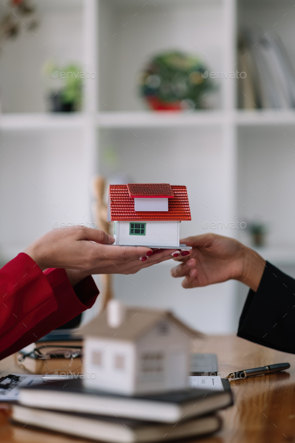 Real estate agent sales manager holding house model to customer after signing rental lease contract