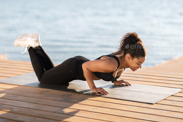 Black woman doing yoga on the beach