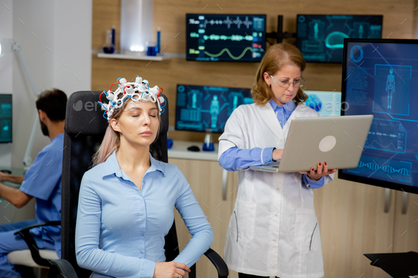 Doctor researching live data on a laptop during a girl\'s brain scan procedure