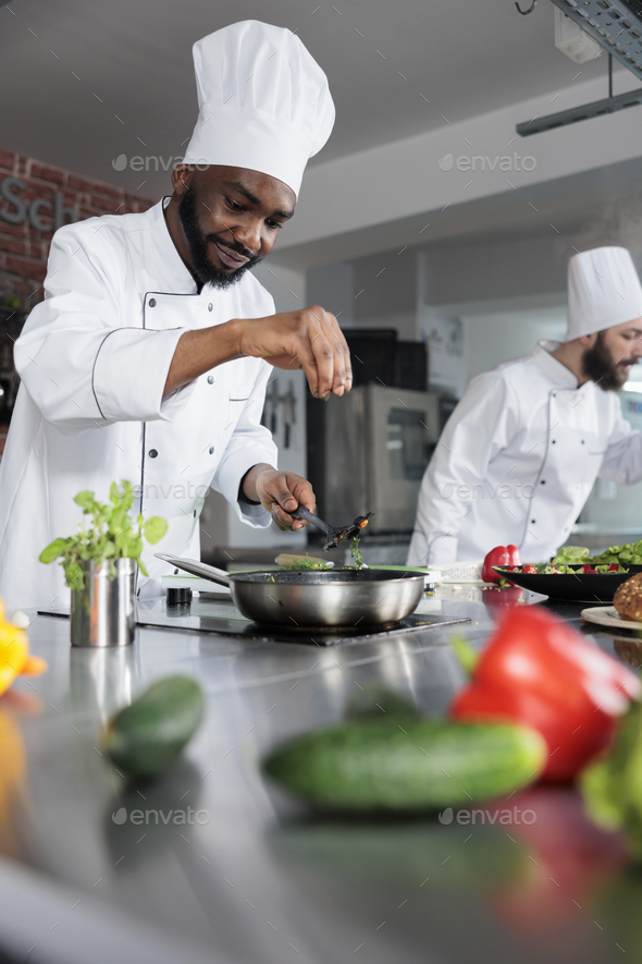 Premium Photo  Food industry worker preparing ingredients for evening meal  in professional kitchen. head chef seasoning gourmet dish in pan while  cooking fine dining food served at dinner service in restaurant.