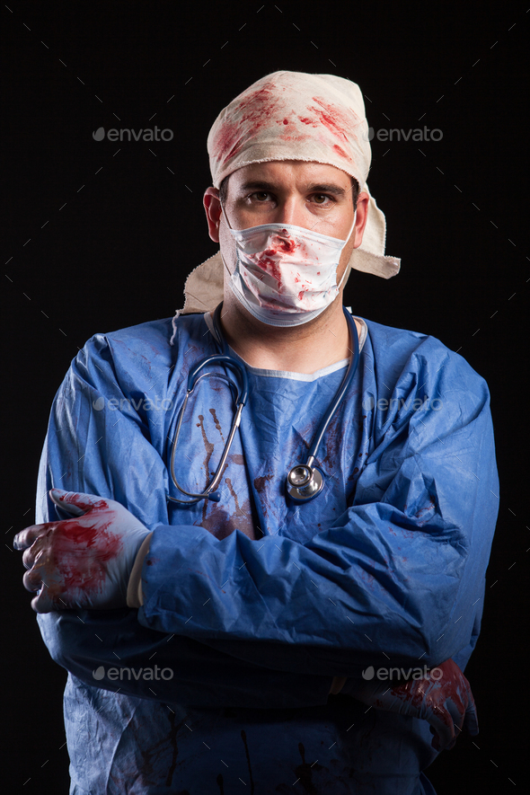 Portrait of young man with arms crossed dressed up like a crazy doctor covered with blood