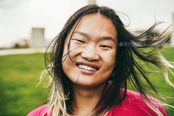 Asian girl smiling on camera at city park - Focus on face - Stock Photo - Images