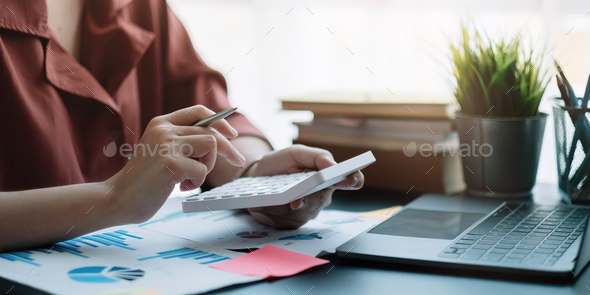 Business woman using calculator for do math finance on wooden desk in office, tax, accounting