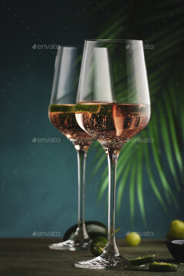 Rose pink wine with jalapeno pepper in wine glass, dark background