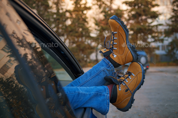 Woman feet on car door. Feet outside the window at sunset forest
