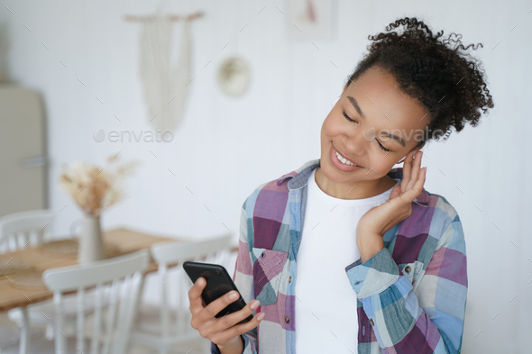 African american young girl listens to music using smartphone at home. Musical apps advertising