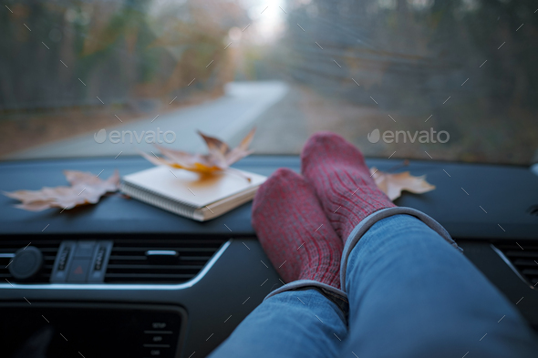 Woman feet in warm socks on car dashboard.