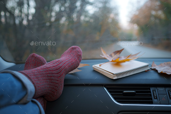 Woman feet in warm socks on car dashboard.