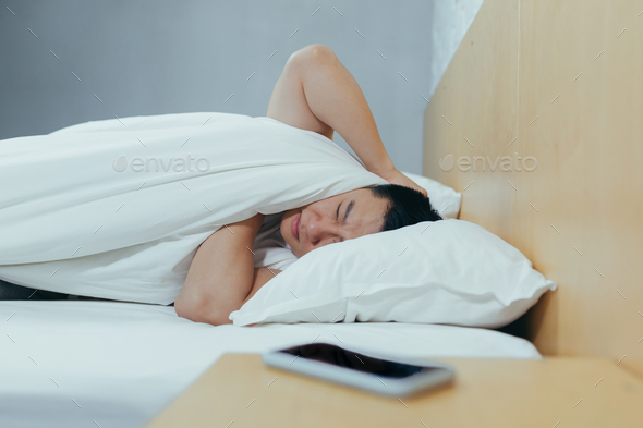 A man at home tries to fall asleep, noisy neighbors interfere with sleep